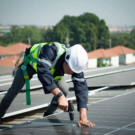 technicien qui installe un kit solaire photovoltaique sur le toit d'une maison. installation en autoconsommation 